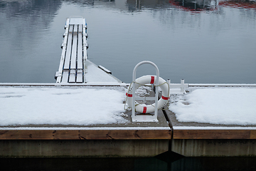 Image showing Snow-Covered Dock With Lifebuoy and Wooden Pier on a Serene Wint