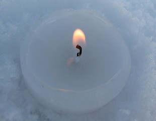 Image showing white lit candle in snowflakes