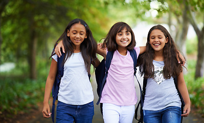 Image showing Happy woman, friends and hug walking with backpack in park for unity, teamwork or school together. Group of young people or teens in nature path with bag for learning, education or outdoor class