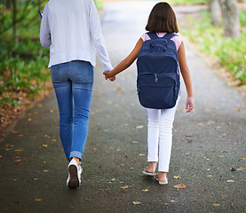 Image showing Woman, teacher and walking student to school in park or outdoor forest for support or responsibility. Rear view of female person or educator holding hands with learner, kid or young child in nature