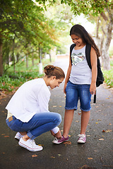 Image showing Woman, teacher and tying student shoes in park for back to school, learning or education in nature. Female person teaching little girl to tie laces on asphalt path, road or outdoor street in woods