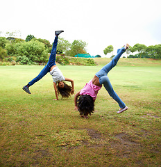 Image showing Happy woman, children and friends in cartwheel on green grass or field together for fun day at the park. Young girls, teens or kids playing and handstands for freedom, activity or games in nature