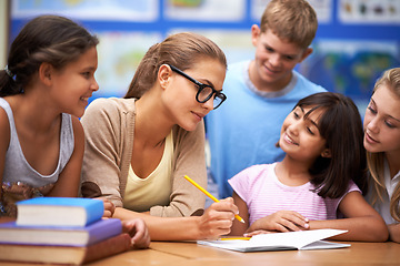 Image showing Teacher, students and writing for learning, education or tutoring in classroom at school. Woman, mentor or educator helping young kids or children with books for studying on literature in class