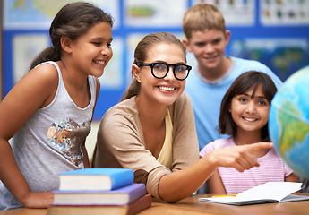 Image showing Happy teacher, portrait and students with globe of planet earth in class for education or learning at school. Woman, mentor or educator smile with young kids or children with world map in classroom