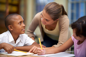 Image showing Happy teacher, students and writing in classroom for education, learning or tutoring at school. Woman, mentor or educator smile for helping kids or children with books in study, library or class