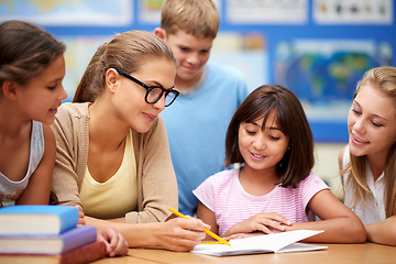 Image showing Happy teacher, students and writing for education, learning or tutoring in classroom at school. Woman, mentor or educator helping young kids or children with books for studying or literature in class