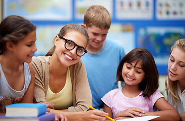 Image showing Happy teacher, students and writing for learning, education or tutoring in classroom at school. Woman, mentor or educator helping young kids or children with books for studying or literature in class