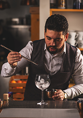 Image showing Bartender is adding ingredient in glass