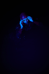 Image showing Authentic triathlete swimmer having a break during hard training on night neon gel light