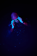 Image showing Authentic triathlete swimmer having a break during hard training on night neon gel light