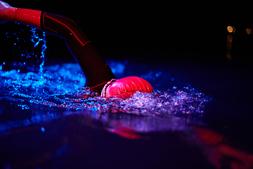 Image showing Authentic triathlete swimmer having a break during hard training on night neon gel light