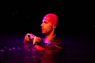 Image showing Authentic triathlete swimmer having a break during hard training on night neon gel light