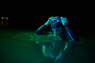 Image showing Authentic triathlete swimmer having a break during hard training on night neon gel light