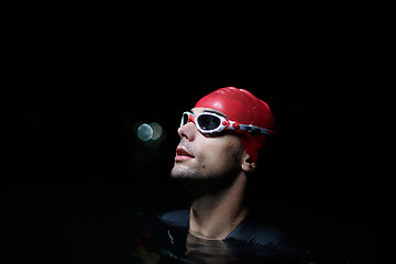 Image showing A determined professional triathlete undergoes rigorous night time training in cold waters, showcasing dedication and resilience in preparation for an upcoming triathlon swim competition