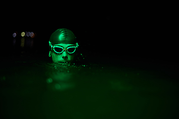 Image showing Authentic triathlete swimmer having a break during hard training on night neon gel light