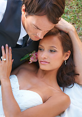 Image showing Couple, embrace and wedding ring for love in outdoors, together and devotion to marriage and commitment. Happy people, romance and hug or relaxing on grass, loyalty and pride for partnership at event