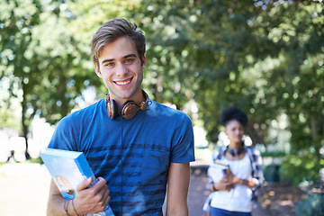 Image showing College, student and portrait of happy man on campus to study on scholarship for education. University, academy and person with book, headphones and walking with smile in park at school after class