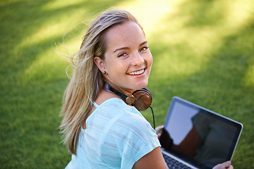 Image showing College, portrait and student with laptop on grass working on research outdoor in park. University, campus and happy woman with computer, headphones and smile for writing notes on project for class