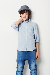 Image showing Portrait, fashion and confident child in a shirt in studio isolated on a white background. Trendy style, cool kid and hat of young boy in jeans, casual clothes and serious on mockup space in Sweden