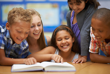 Image showing Children, teacher and reading a book in classroom for knowledge, learning or education with happiness. Group, student and woman at school with study, textbook and smile with diversity at college