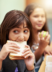 Image showing Girl, face and student biting sandwich for meal, break or snack time in classroom at school. Hungry young kid or elementary child eating bread for food, fiber and nutrition in class during recess
