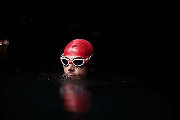 Image showing A determined professional triathlete undergoes rigorous night time training in cold waters, showcasing dedication and resilience in preparation for an upcoming triathlon swim competition