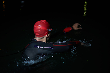 Image showing A determined professional triathlete undergoes rigorous night time training in cold waters, showcasing dedication and resilience in preparation for an upcoming triathlon swim competition