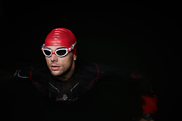 Image showing A determined professional triathlete undergoes rigorous night time training in cold waters, showcasing dedication and resilience in preparation for an upcoming triathlon swim competition