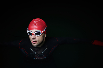 Image showing A determined professional triathlete undergoes rigorous night time training in cold waters, showcasing dedication and resilience in preparation for an upcoming triathlon swim competition