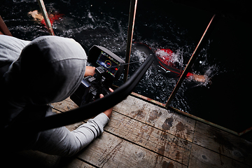 Image showing Videographer taking action shot of triathlon swimming athlete at night