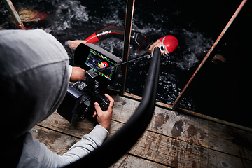 Image showing Videographer taking action shot of triathlon swimming athlete at night