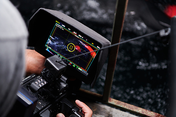 Image showing Videographer taking action shot of triathlon swimming athlete at night