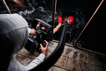 Image showing Videographer taking action shot of triathlon swimming athlete at night