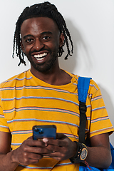 Image showing African American teenager engages with his smartphone against a pristine white background, encapsulating the essence of contemporary digital connectivity and youth culture