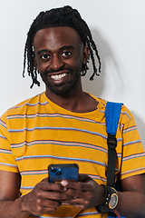 Image showing African American teenager engages with his smartphone against a pristine white background, encapsulating the essence of contemporary digital connectivity and youth culture