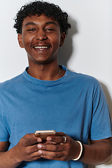 Image showing African American teenager engages with his smartphone against a pristine white background, encapsulating the essence of contemporary digital connectivity and youth culture