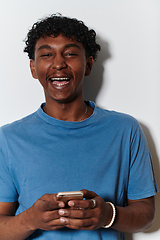 Image showing African American teenager engages with his smartphone against a pristine white background, encapsulating the essence of contemporary digital connectivity and youth culture