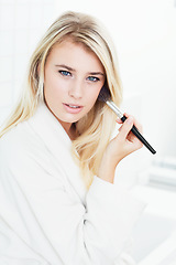 Image showing Young woman, portrait and brushing makeup for cosmetics or facial treatment in bathroom at home. Face of attractive or gorgeous blonde female person or model applying foundation or skincare at house