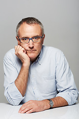 Image showing Serious, portrait and senior businessman in a studio with pride for legal corporate career. Glasses, table and professional elderly male lawyer with bored face expression isolated by gray background.