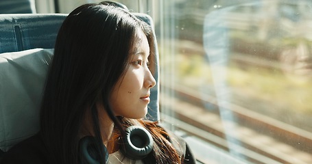 Image showing Japanese woman, window and train with headphones, travel and public transportation on metro bullet. Young person, thinking and relax on fast vehicle for weekend trip and wellness by audio technology