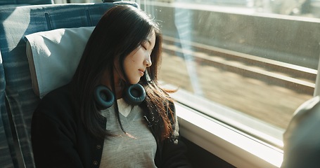 Image showing Japanese woman, sleeping and train with travel, headphones and public transportation on metro bullet. Young person, tired and rest on fast vehicle for weekend trip and commute with audio technology