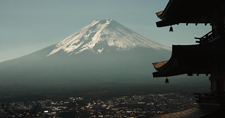 Image showing Chureito Pagoda, Mount Fuji and city in morning with temple, trees and blue sky on travel. Japanese architecture, culture and spiritual history with view of mountain, snow and calm Asian landscape.