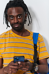 Image showing African American teenager engages with his smartphone against a pristine white background, encapsulating the essence of contemporary digital connectivity and youth culture