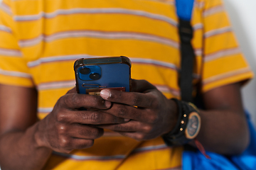 Image showing African American teenager engages with his smartphone against a pristine white background, encapsulating the essence of contemporary digital connectivity and youth culture