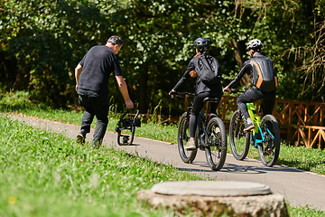 Image showing A professional videographer skillfully captures the joyous journey of a couple on bicycles through the park, blending cinematic expertise with the natural allure of outdoor adventure