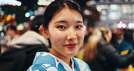 Image showing Japanese woman, portrait and night in city, busy urban street or crowd on commute, walk and outdoor. Girl, person and happy for vacation, exploring or journey on metro sidewalk for adventure in Tokyo