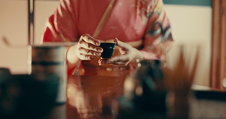 Image showing Hands of woman in traditional Japanese tea house, kimono and relax with mindfulness, respect and service. Girl at calm tearoom with matcha drink in cup, zen culture and ritual at table for ceremony.
