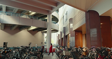 Image showing City, walking and woman in building with bicycle for travelling, commute and bike parking or station. Transport, urban town and Japanese person with storage for sustainable vehicles for journey