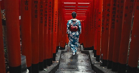 Image showing Woman, shinto religion and walk by gates in japan, spiritual path and indigenous culture in kimono. Person, traditional clothes or worship in peace, respect or beauty by Fushimi Inari Taisha in kyoto
