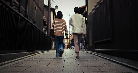 Image showing Women, walking and back by city street and travel for bonding in urban town in winter. Friends, wellness and commute together in neighborhood for social trip, vacation and outdoor in tokyo on journey